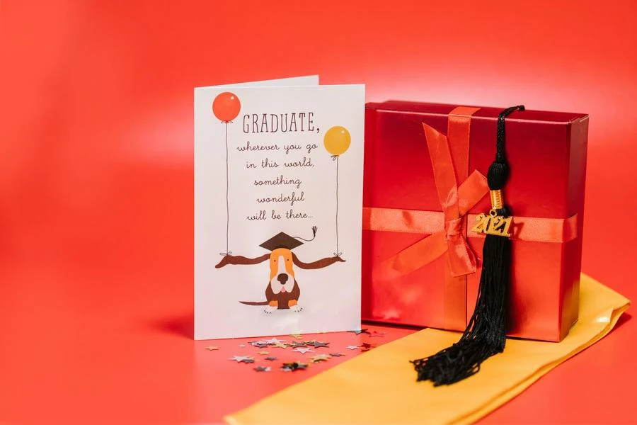 A graduation greeting card placed next to a  red gift box