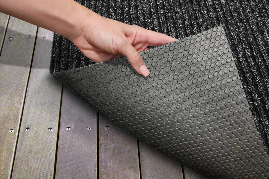 A hand holding a black outdoor carpet