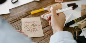 A person writing a Mother's Day greeting card
