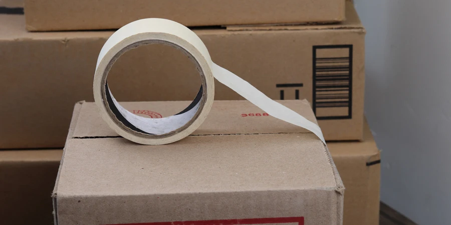 Un rollo de cinta adhesiva sobre una caja de cartón.