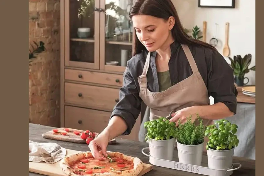 Une femme aromatisant la pizza aux herbes provenant d'une capsule de ferme intérieure