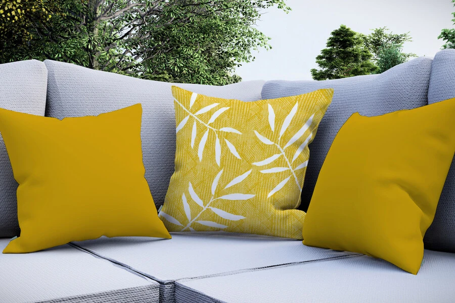 Cojines de exterior color plátano sobre un sofá gris