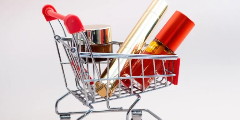 Front view of a shopping cart with makeup products on a pink background
