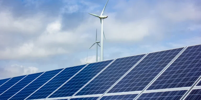 Solar panels and wind turbine against blue sky