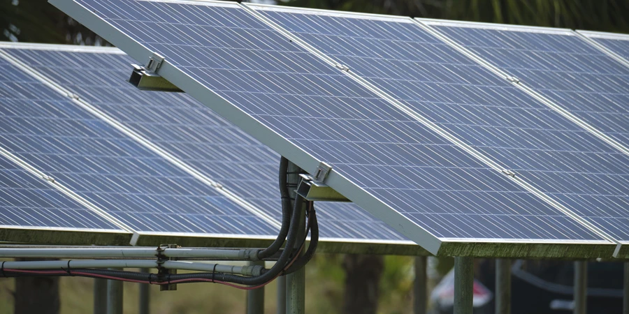 Солнечные панели установлены на каркасе стенда возле парковки для эффективного производства экологически чистой электроэнергии.