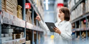 Trabajadora de almacén que utiliza tabletas digitales para comprobar el inventario de existencias en los estantes de grandes almacenes