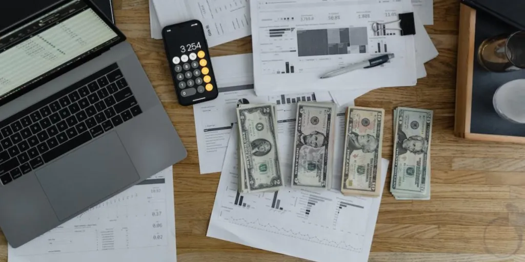 Laptop, kalkulator, dan uang dengan laporan bisnis