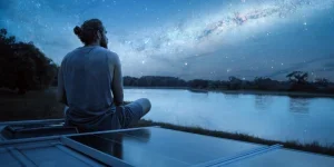 A man far from the city sits near a solar panel