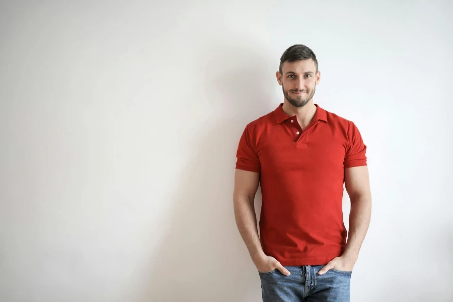 A man wearing a red polo shirt on blue jeans