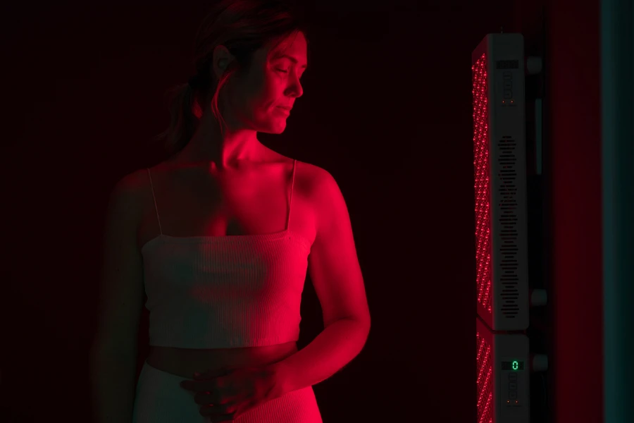 Una mujer frente a un dispositivo de terapia de luz roja.