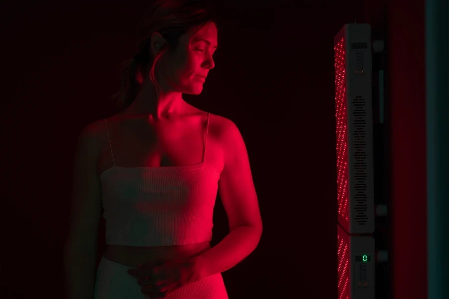 A woman in front of a red light therapy device