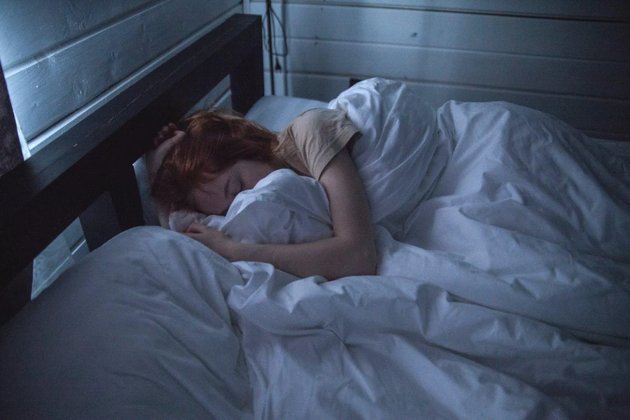 Uma mulher dormindo em um edredom branco simples