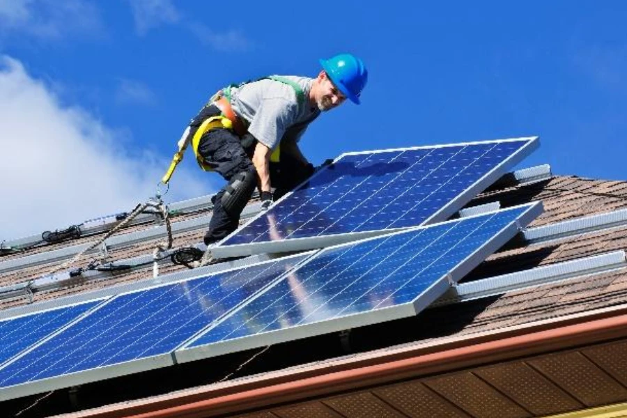 Seorang pekerja memasang panel surya di atap