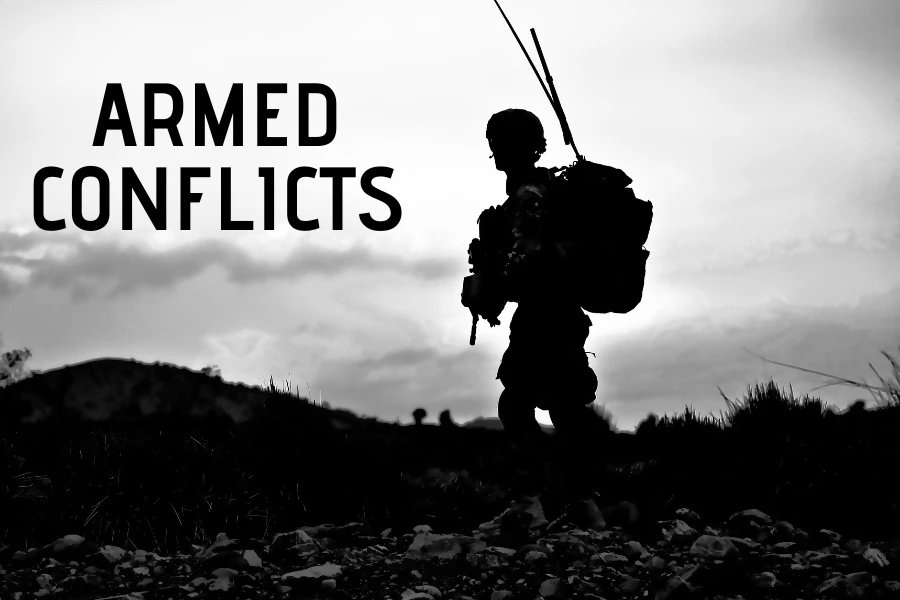 Soldado armado con equipo de combate parado en un campo devastado