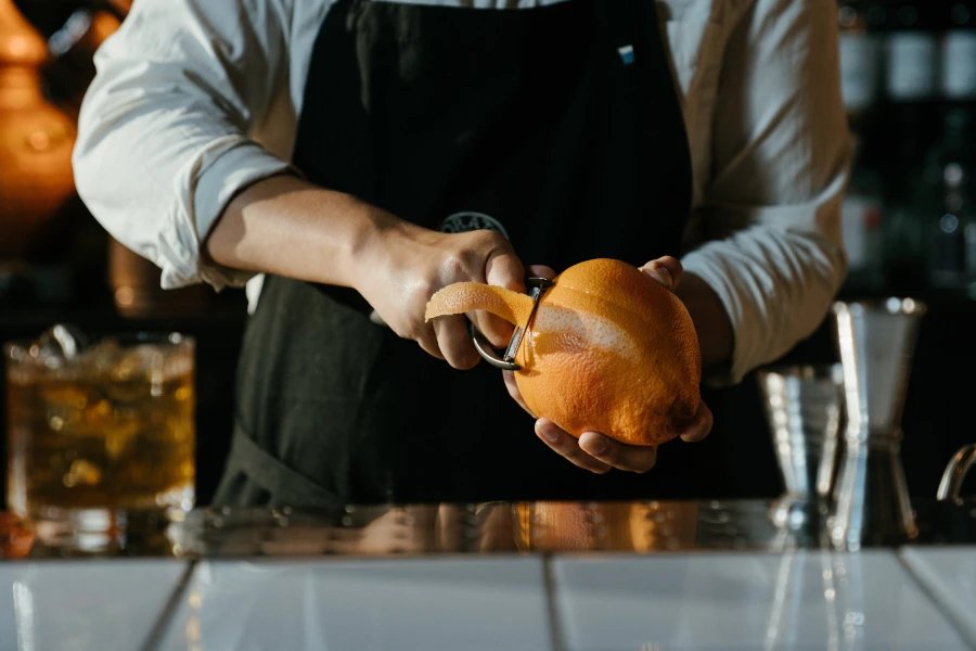Bartender peeling the skin of an orange