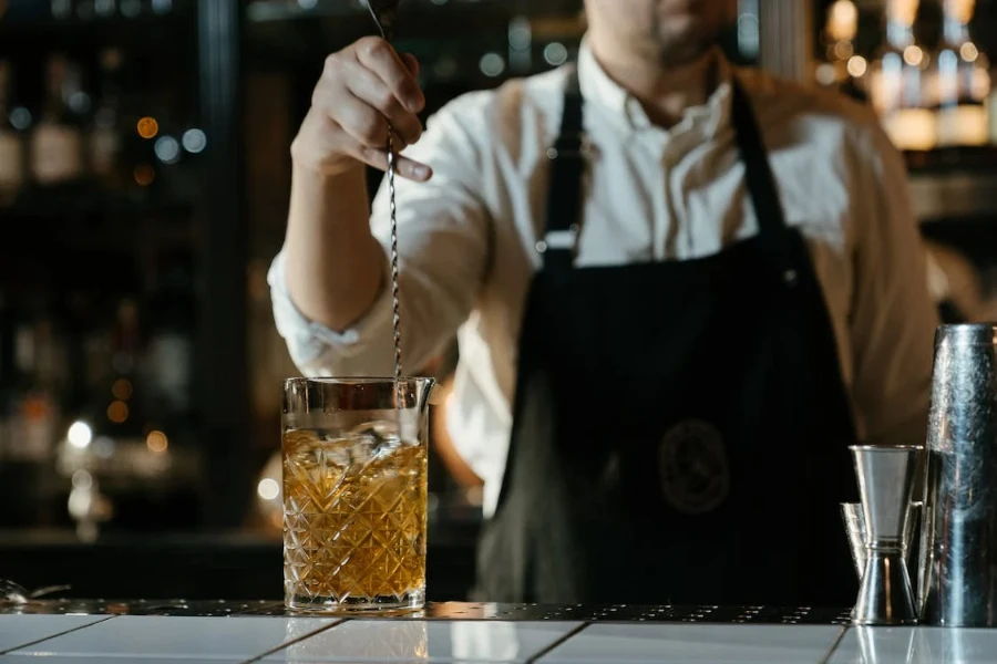 Camarero usando una cuchara de bar para mezclar una bebida