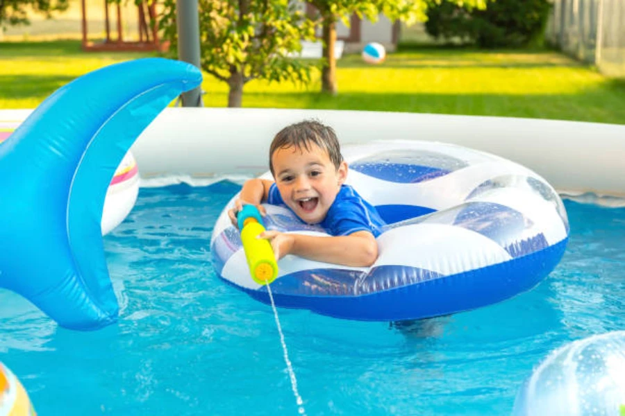 Boy in inflatable donut shooting water from foam water cannon