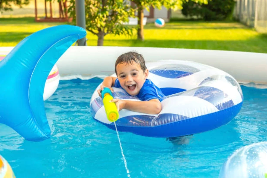 Niño en donut inflable disparando agua desde un cañón de agua de espuma