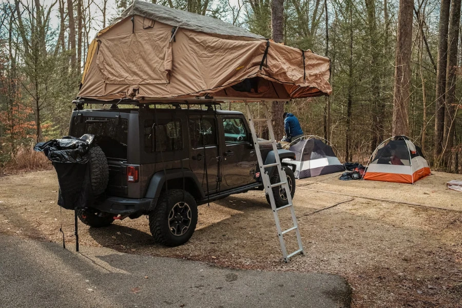 Aufbau eines braunen Dachzeltes auf einem Geländewagen im Wald