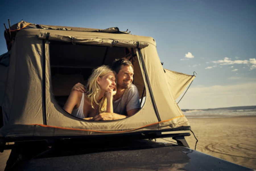 Couple lying down in tent parked on beach