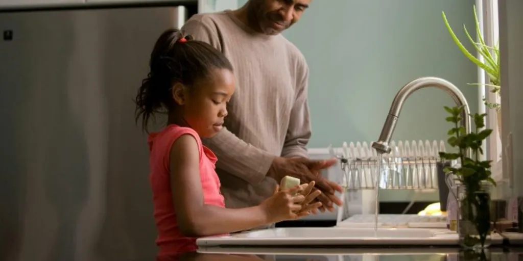 Father and daughter washing hands at a kitchen sink