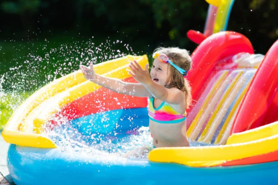 Chica aterrizando en una pequeña piscina con tobogán inflable