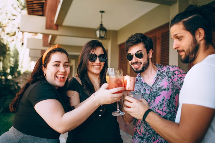 Группа друзей улыбается, пьет коктейли