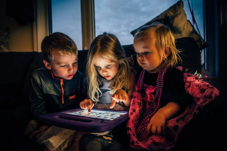 Gruppo di tre bambini piccoli che guardano un tablet