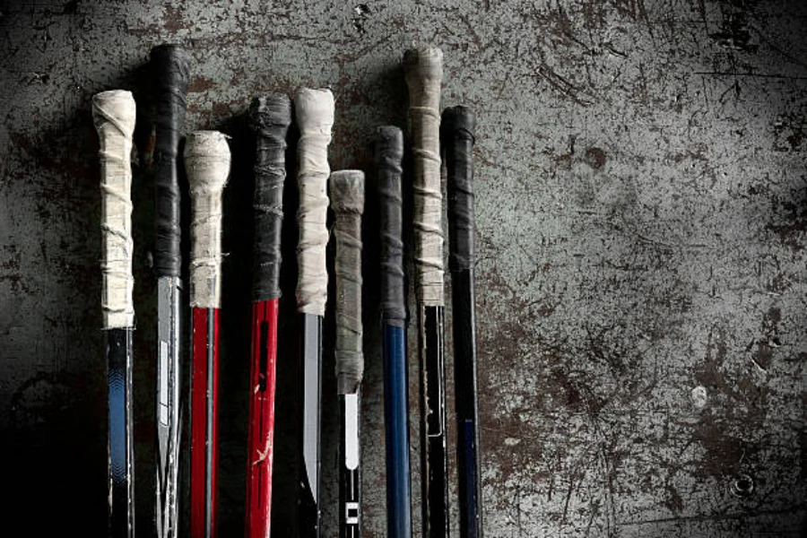 Ice hockey sticks lined up against wall of hockey rink