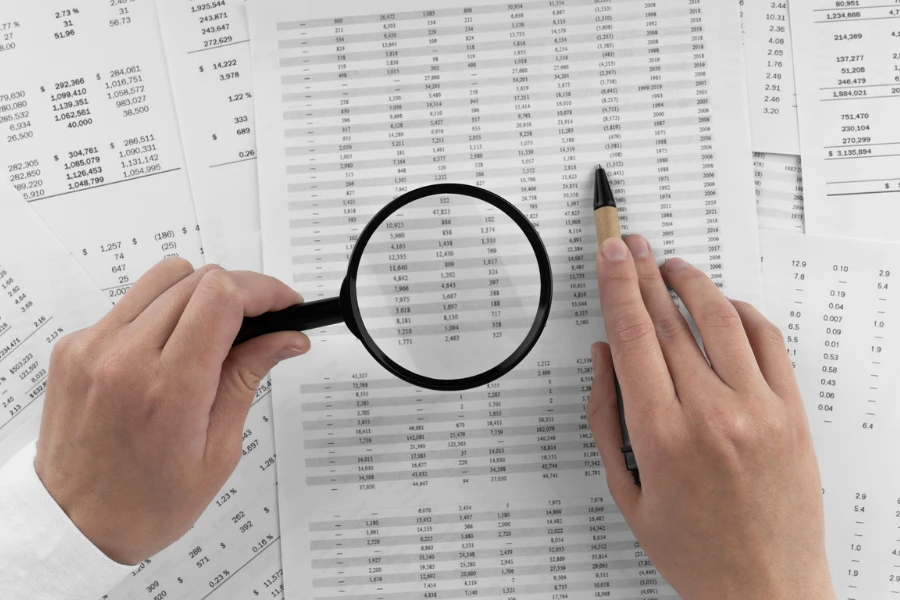 Magnifying glass examining financial balance sheets closely