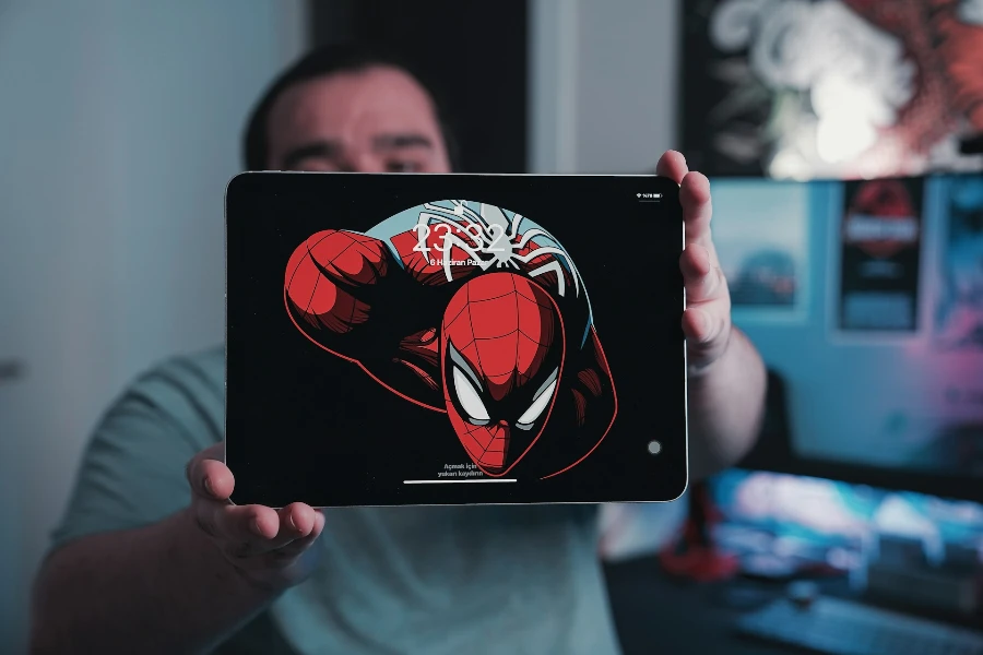 スパイダーマンの壁紙が表示された iPad タブレットを持っている男性