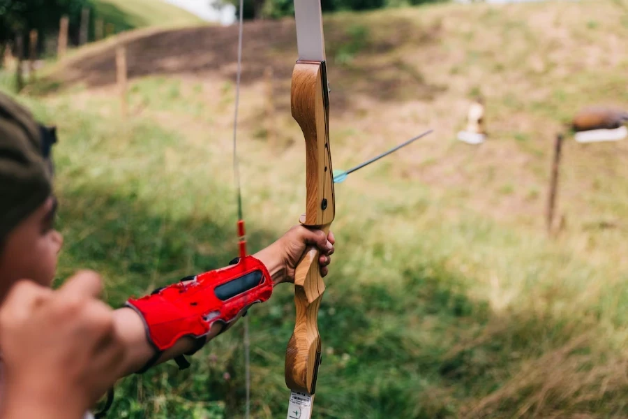 Man lining up to shoot arrow using wooden bow