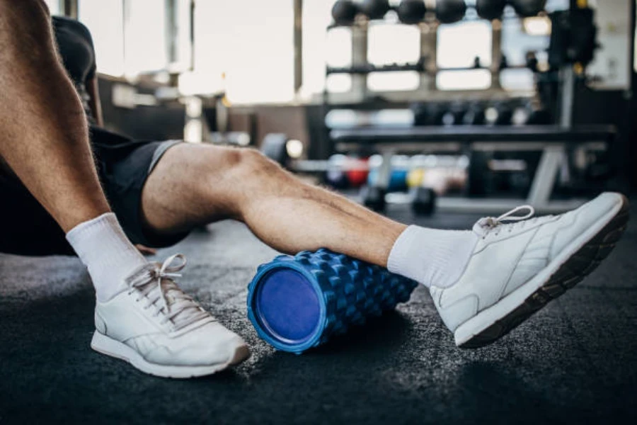 Man using blue foam roller to massage his left calf