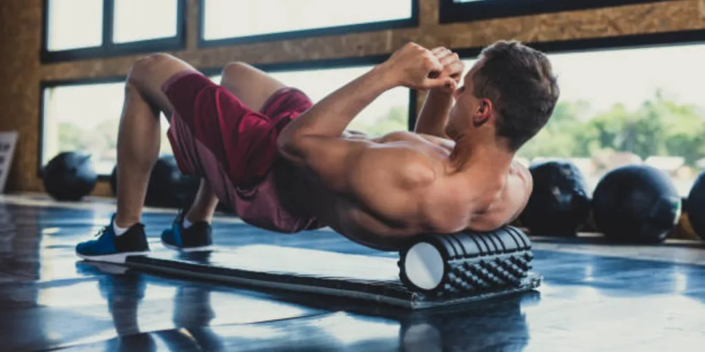 Man using foam roller on his back in the gym