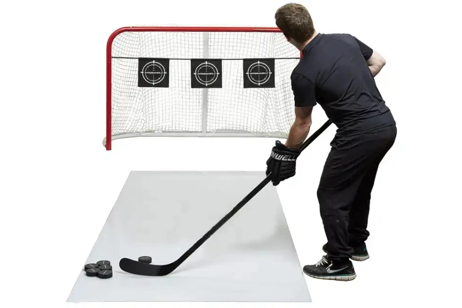 Homme utilisant des tapis de tir de hockey comme cible d'entraînement hors glace