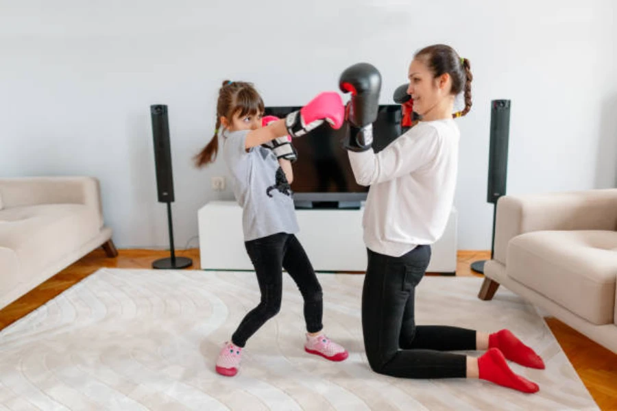 Madre e hija usando guantes de boxeo en la sala de estar