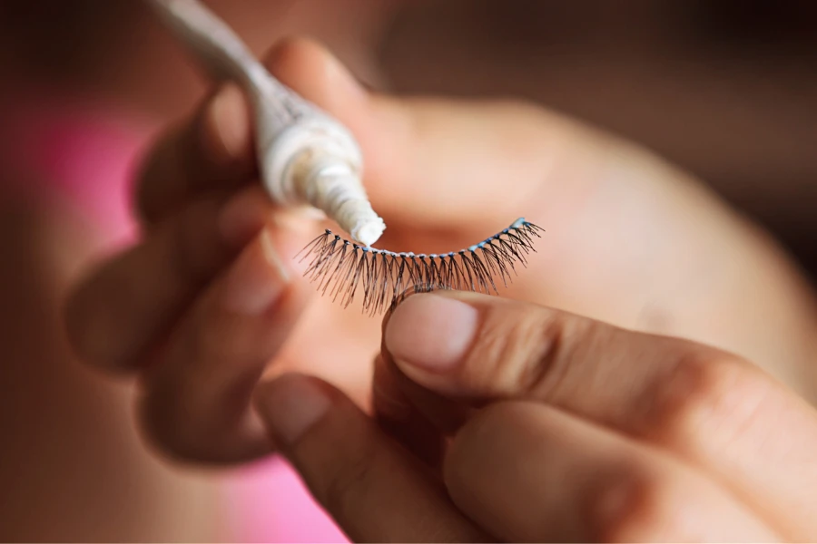 Person applying glue to a lash extension