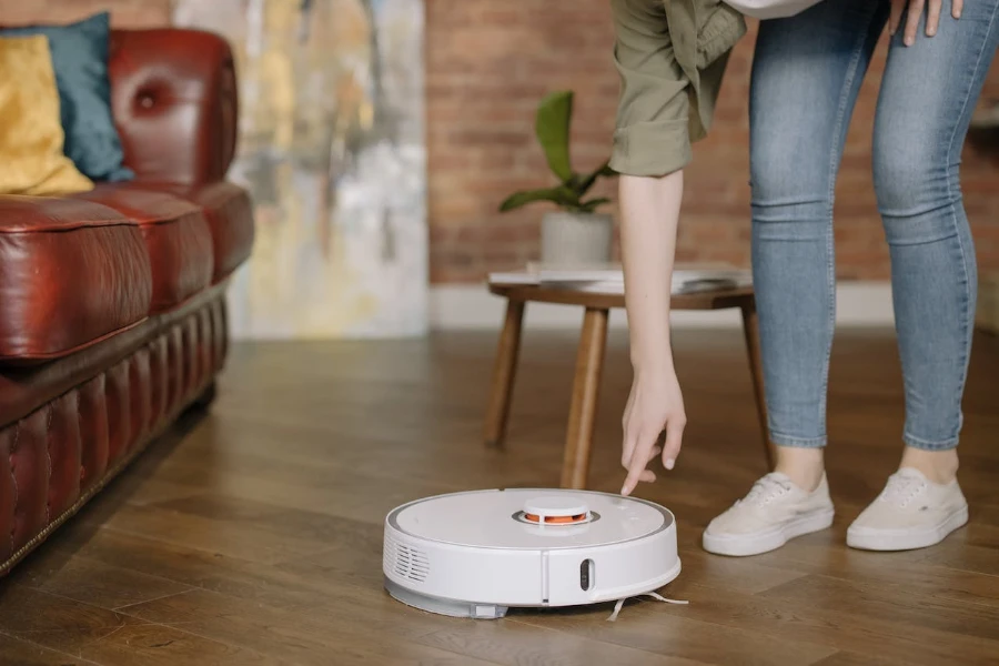 Person leaning down to press a button on a robot vacuum
