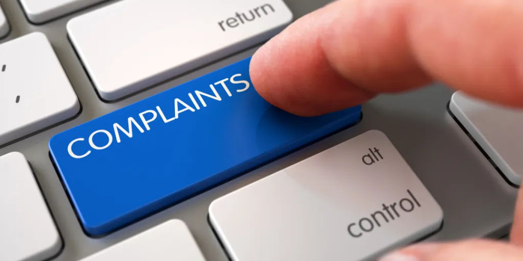 Person pressing a “COMPLAINTS” button on a keyboard