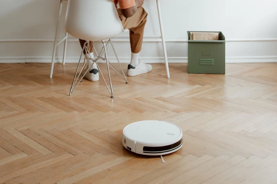 Personne assise au bureau avec un robot aspirateur travaillant derrière elle