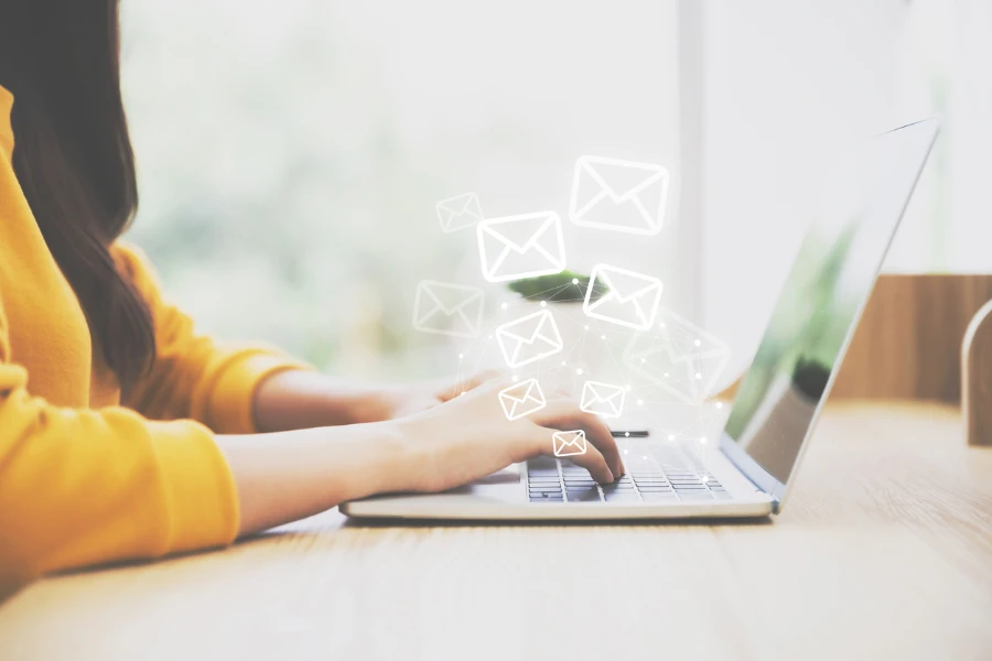 Persona escribiendo en una computadora con íconos de correo electrónico arriba