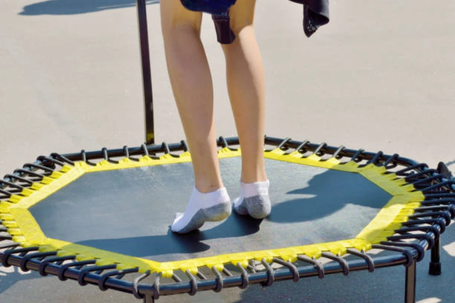 Çorap giyerken egzersiz yapmak için mini trambolin kullanan kişi