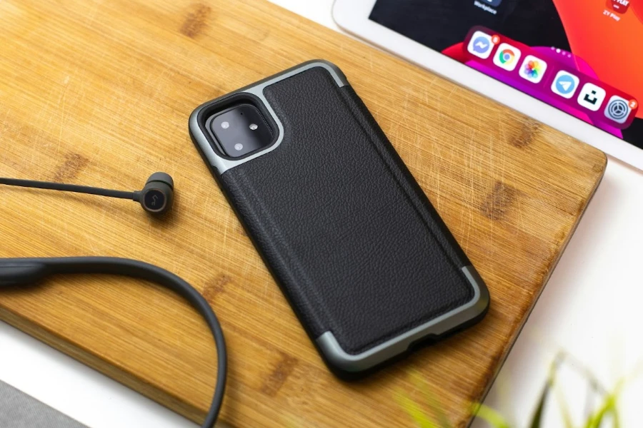 Phone in a black case sitting beside a set of headphones