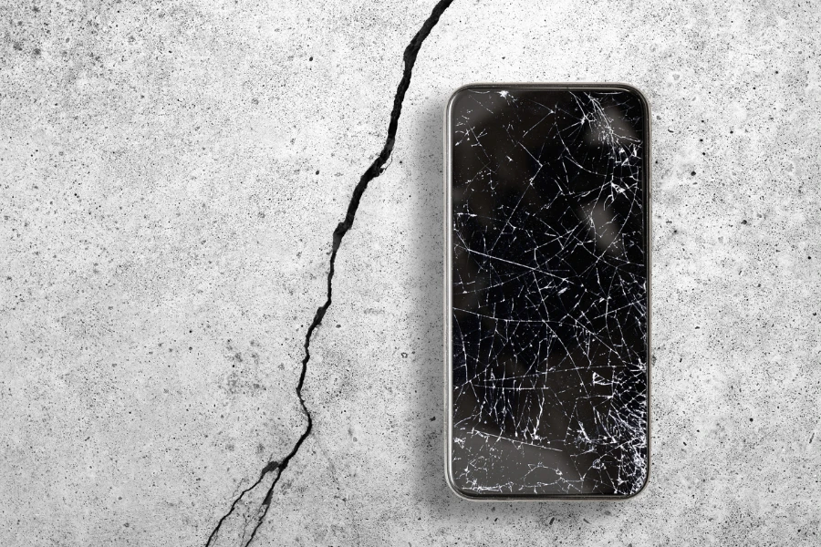 Phone sitting on the concrete with a cracked screen