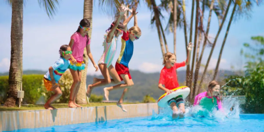 Six enfants sautant dans la piscine avec des jouets à l'extérieur