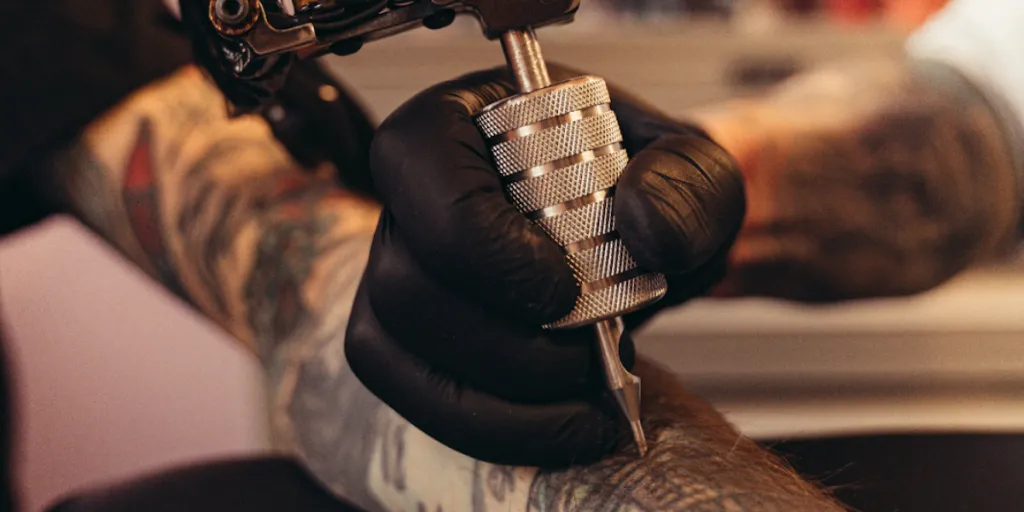 Şık bir dövme tabancası kullanan dövme sanatçısı