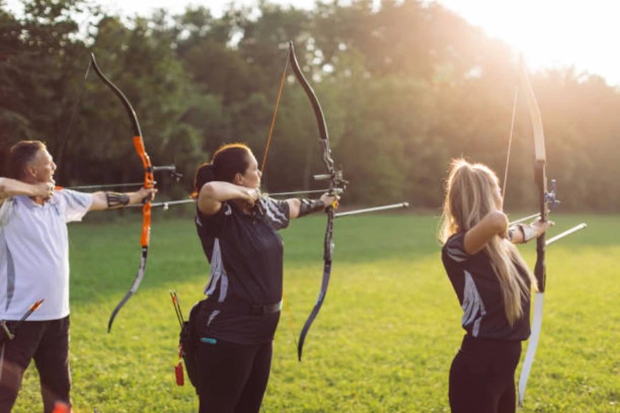 Three people lined up ready to shoot with barebows
