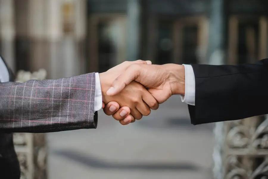 Dua profesional bisnis berjabat tangan dalam persetujuan