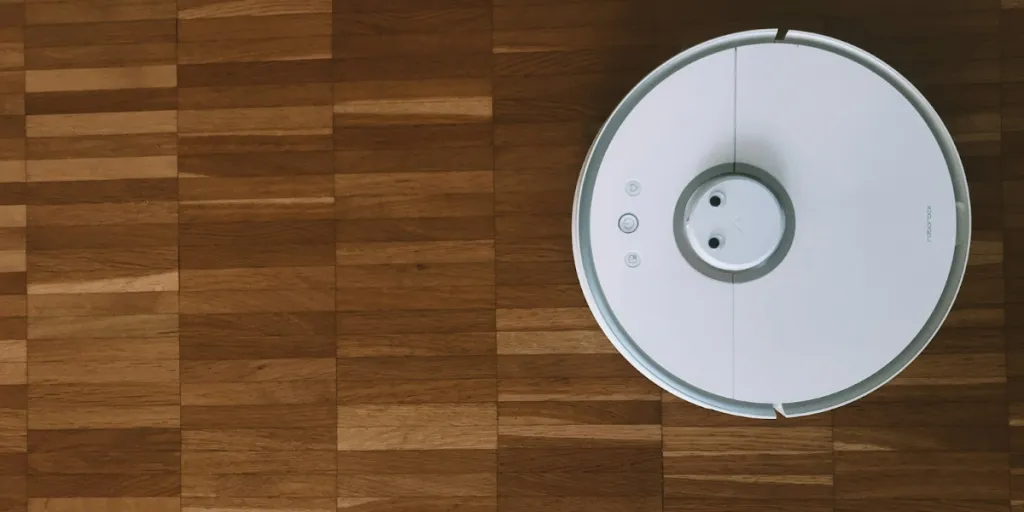 Penyedot debu robot putih di lantai kayu