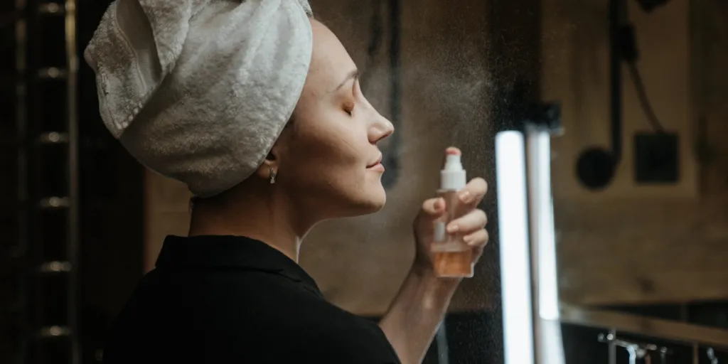 Femme appliquant un spray fixateur de maquillage